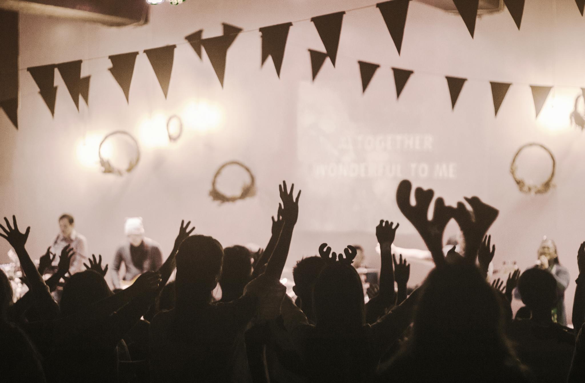 Vibrant concert scene with a cheering crowd and musicians on stage, featuring lively lights and festive decor.